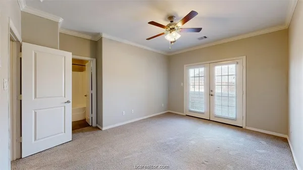 an empty room with chandelier fan and windows