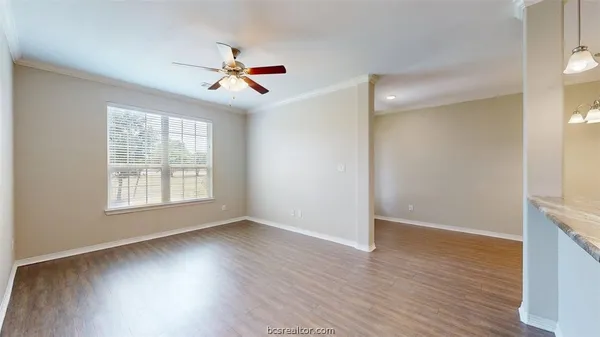 a view of an empty room with wooden floor and a window