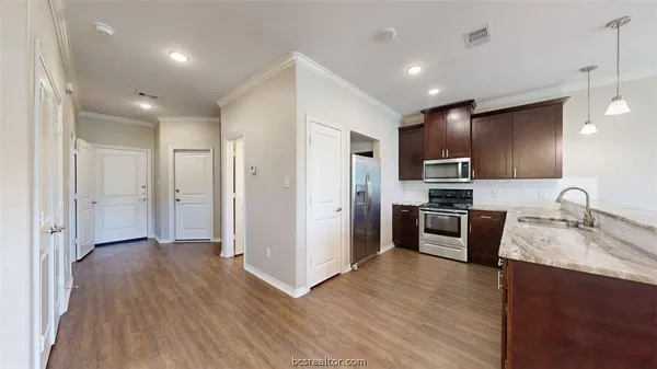 a kitchen with stainless steel appliances granite countertop a refrigerator a sink dishwasher a oven with wooden cabinets and wooden floor