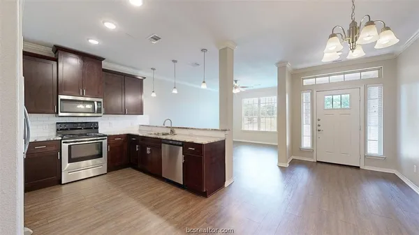 a large kitchen with stainless steel appliances granite countertop a stove and a wooden floors