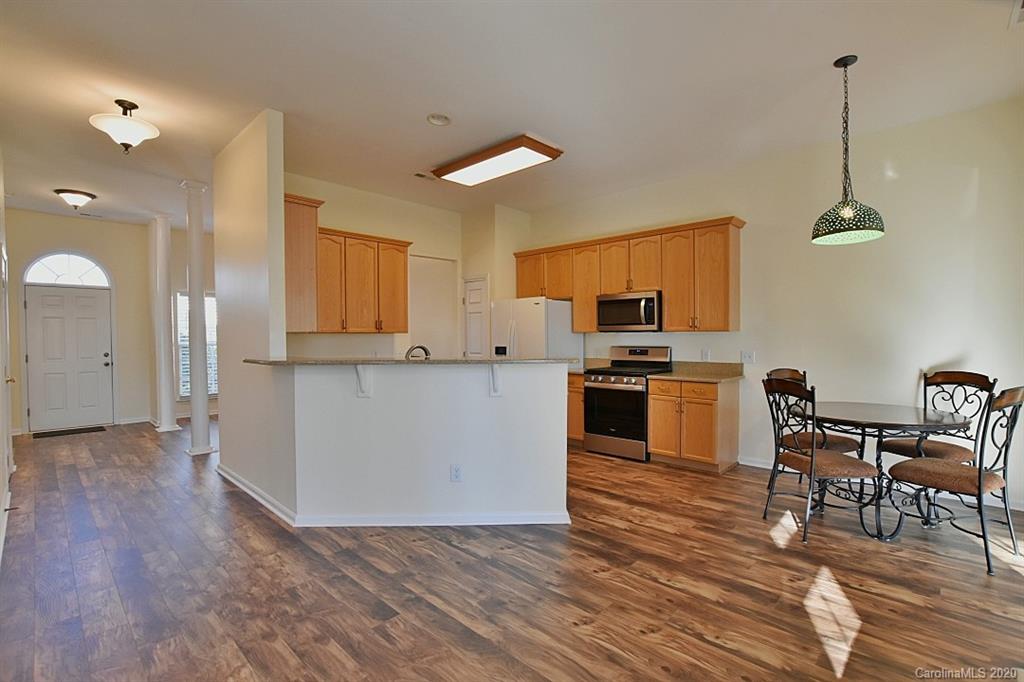 1132 Gower Street Fort Mill, SC 29708 - Photo 8 of 27 a kitchen with granite countertop a stove a sink a dining table and chairs with wooden floor