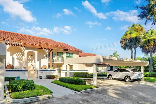 a view of a blue house with a big yard and potted plants
