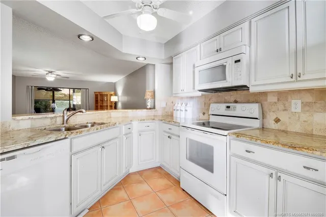 a kitchen with white cabinets appliances and a sink