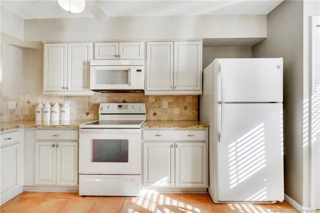 a kitchen with white cabinets and white appliances