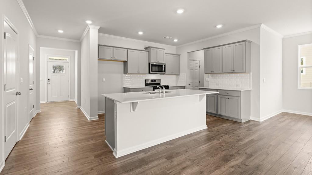 4083 Peregrine Way Gainesville, GA 30506 - Photo 4 of 34 a kitchen with kitchen island a sink a stove a refrigerator and white cabinets