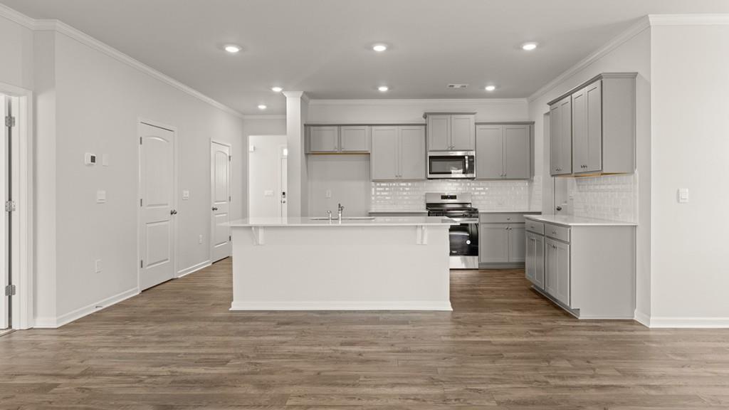 4083 Peregrine Way Gainesville, GA 30506 - Photo 5 of 34 a large kitchen with kitchen island a sink a stove a refrigerator and white cabinets