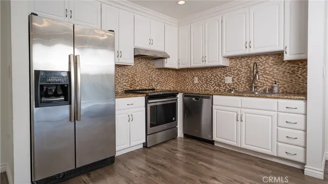 a kitchen with white cabinets and stainless steel appliances
