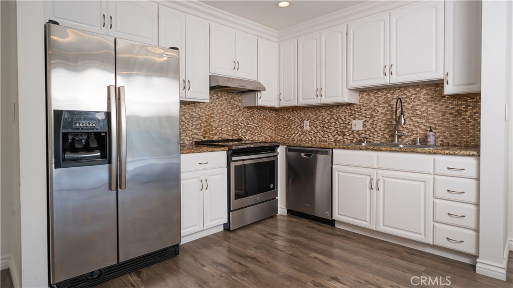 102 Scholz Plaza, Unit 37 Newport Beach, CA 92663 - Photo 3 of 12 a kitchen with white cabinets and stainless steel appliances