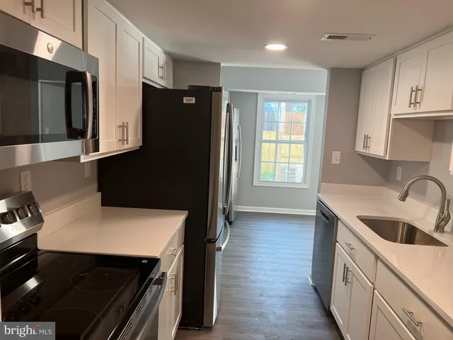 a kitchen with stainless steel appliances a stove a sink a refrigerator and wooden cabinets