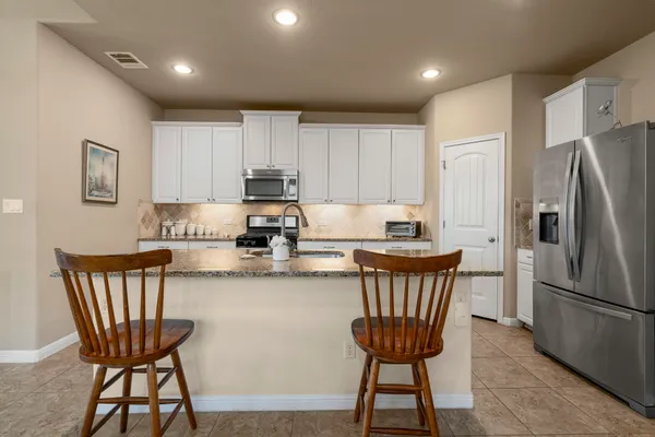 a kitchen with stainless steel appliances granite countertop a dining table chairs microwave and sink