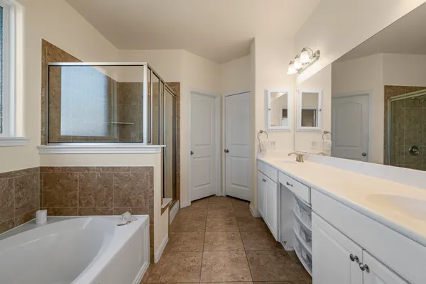 a spacious bathroom with a tub sink and mirror