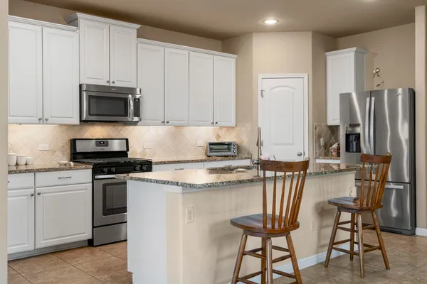 a kitchen with stainless steel appliances granite countertop a stove a sink and a microwave