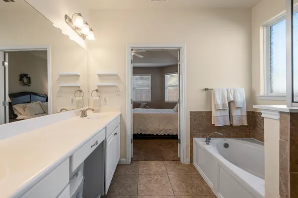 a en suite bathroom with a tub double sink and mirror