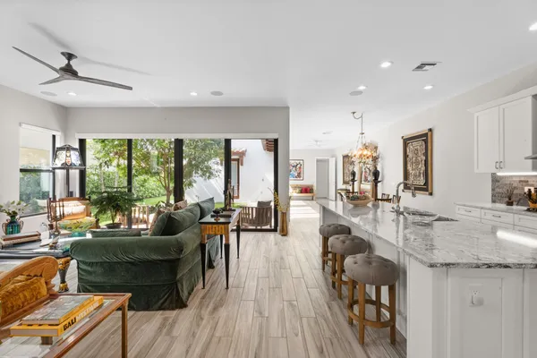 a living room with kitchen island granite countertop wooden floor a couch and a large window