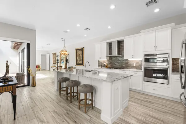a kitchen with stainless steel appliances kitchen island granite countertop a stove a sink a refrigerator and cabinets