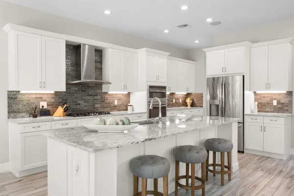 a kitchen with stainless steel appliances granite countertop a refrigerator a stove a sink a dining table and chairs