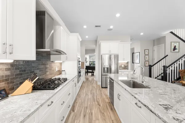 a large kitchen with stainless steel appliances granite countertop a lot of counter space and wooden floors