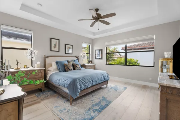 a spacious bedroom with a large bed a chandelier and windows