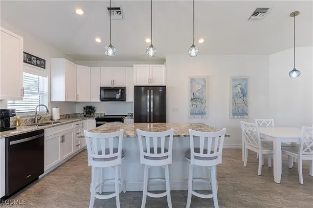 a large kitchen with granite countertop a island a sink stainless steel appliances and white cabinets