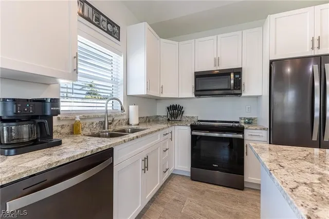 a kitchen with granite countertop a sink stainless steel appliances and white cabinets