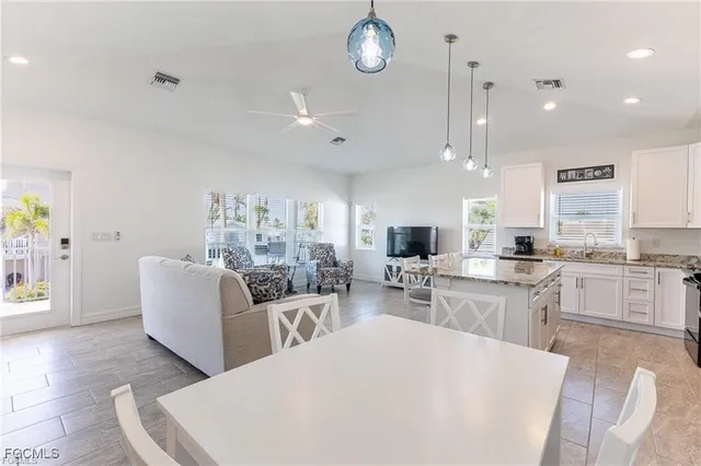a large white kitchen with cabinets a island a sink and stainless steel appliances