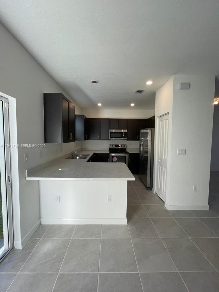 2634 Southeast 11th Court, Unit 2634 Homestead, FL 33035 - Photo 6 of 20 a large white kitchen with a sink and a refrigerator