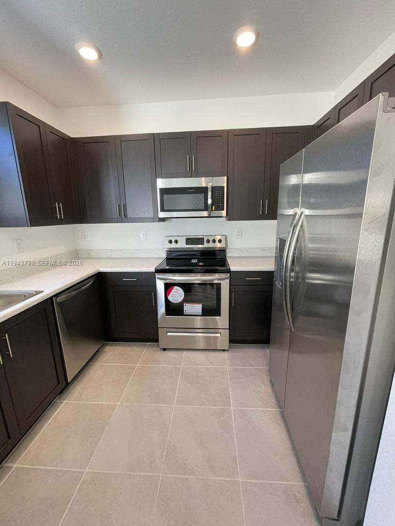2634 Southeast 11th Court, Unit 2634 Homestead, FL 33035 - Photo 9 of 20 a kitchen with stainless steel appliances a stove a sink and a refrigerator