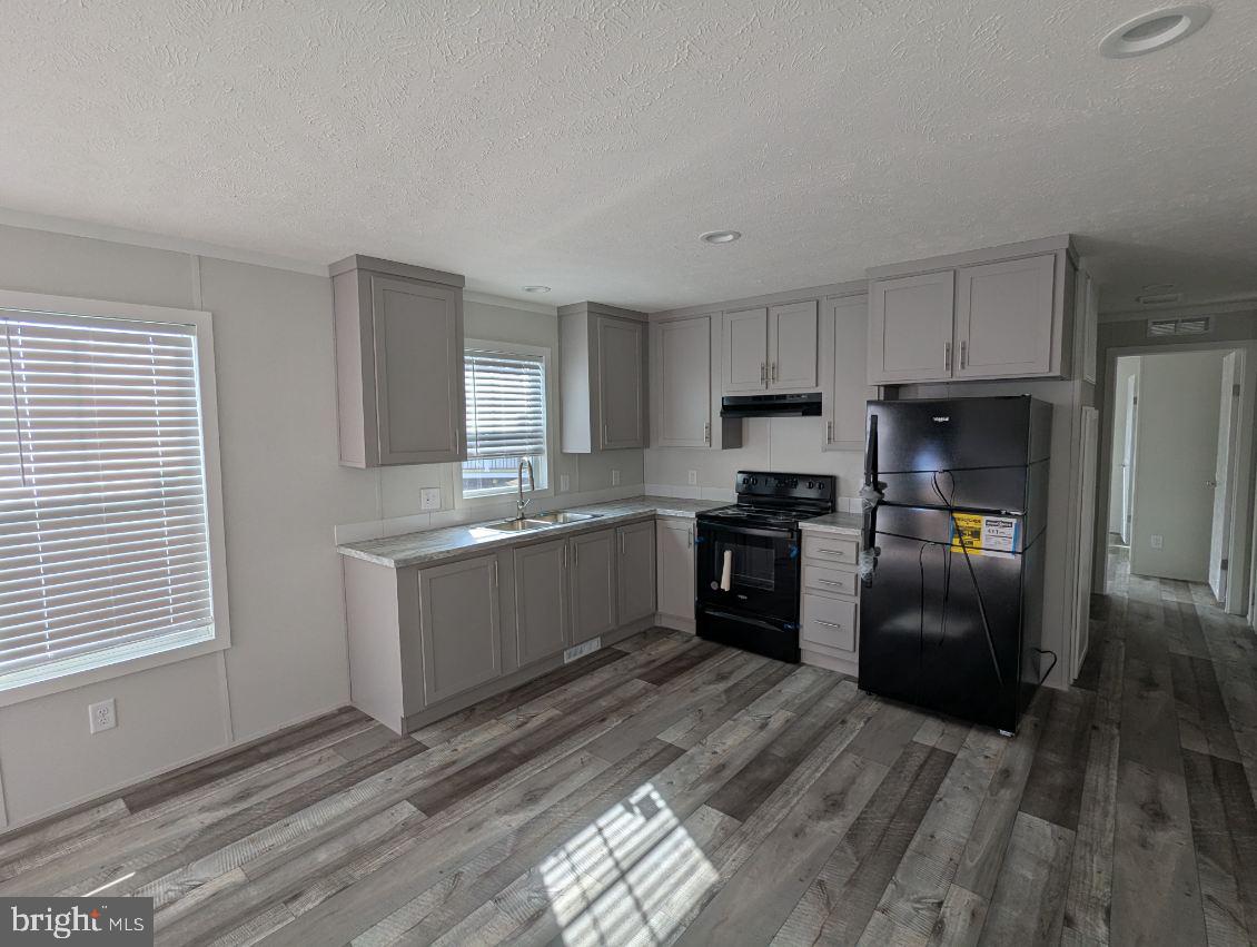 12623 Shell Mill Road, Unit 54 Bishopville, MD 21813 - Photo 4 of 24 a kitchen with granite countertop a refrigerator oven a sink dishwasher and wooden cabinets with wooden floor