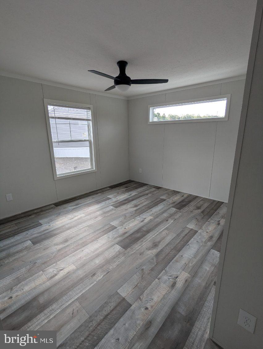 12623 Shell Mill Road, Unit 54 Bishopville, MD 21813 - Photo 8 of 24 an empty room with wooden floor fan and windows