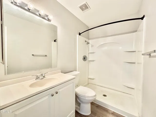 a bathroom with a sink vanity granite toilet and shower
