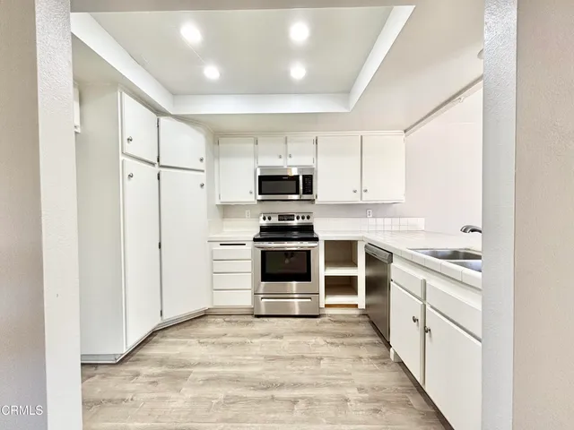 a kitchen with white cabinets and appliances