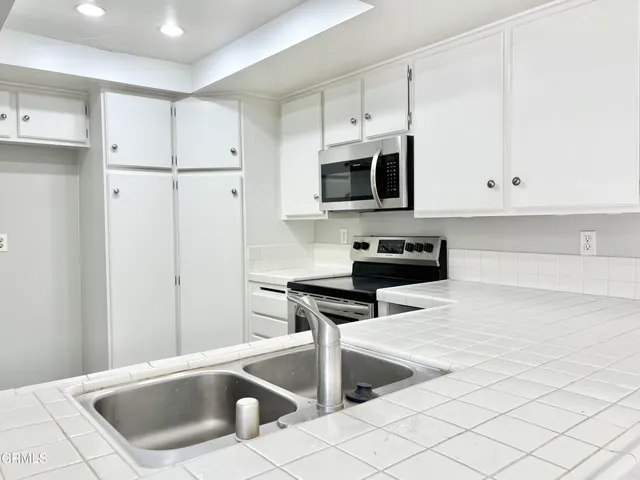 a kitchen with granite countertop white cabinets and stainless steel appliances