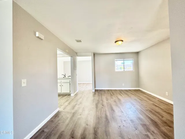 a view of an empty room with window and wooden floor