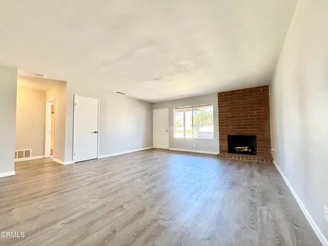 a view of an empty room with a window and fireplace