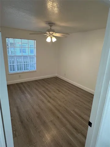 an empty room with wooden floor cabinet and windows