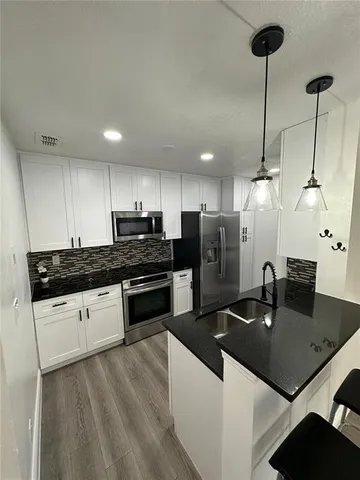 a kitchen with stainless steel appliances granite countertop a sink a stove and refrigerator
