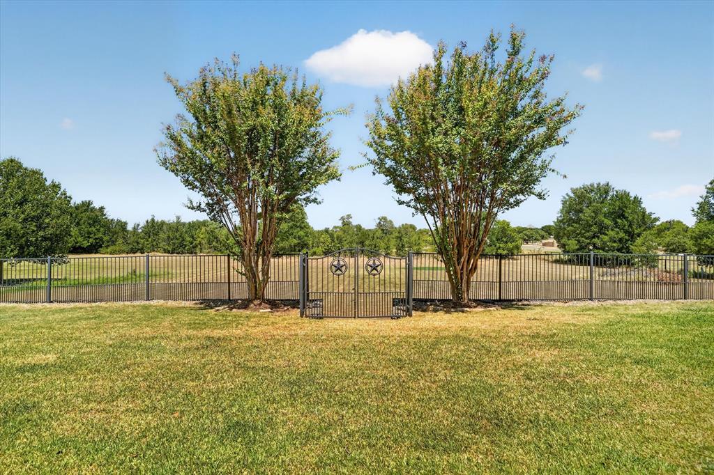 100 Canyon Ridge Trail Aledo, TX 76008 - Photo 35 of 38 Manicured lawn with a wrought iron fence featuring a decorative gate and two mature trees