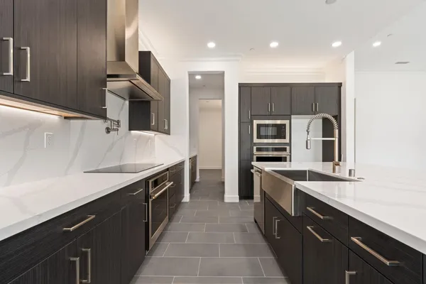 a large kitchen with stainless steel appliances a sink and a refrigerator