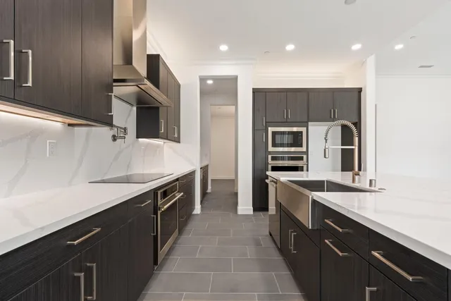 a large kitchen with stainless steel appliances a sink and a refrigerator
