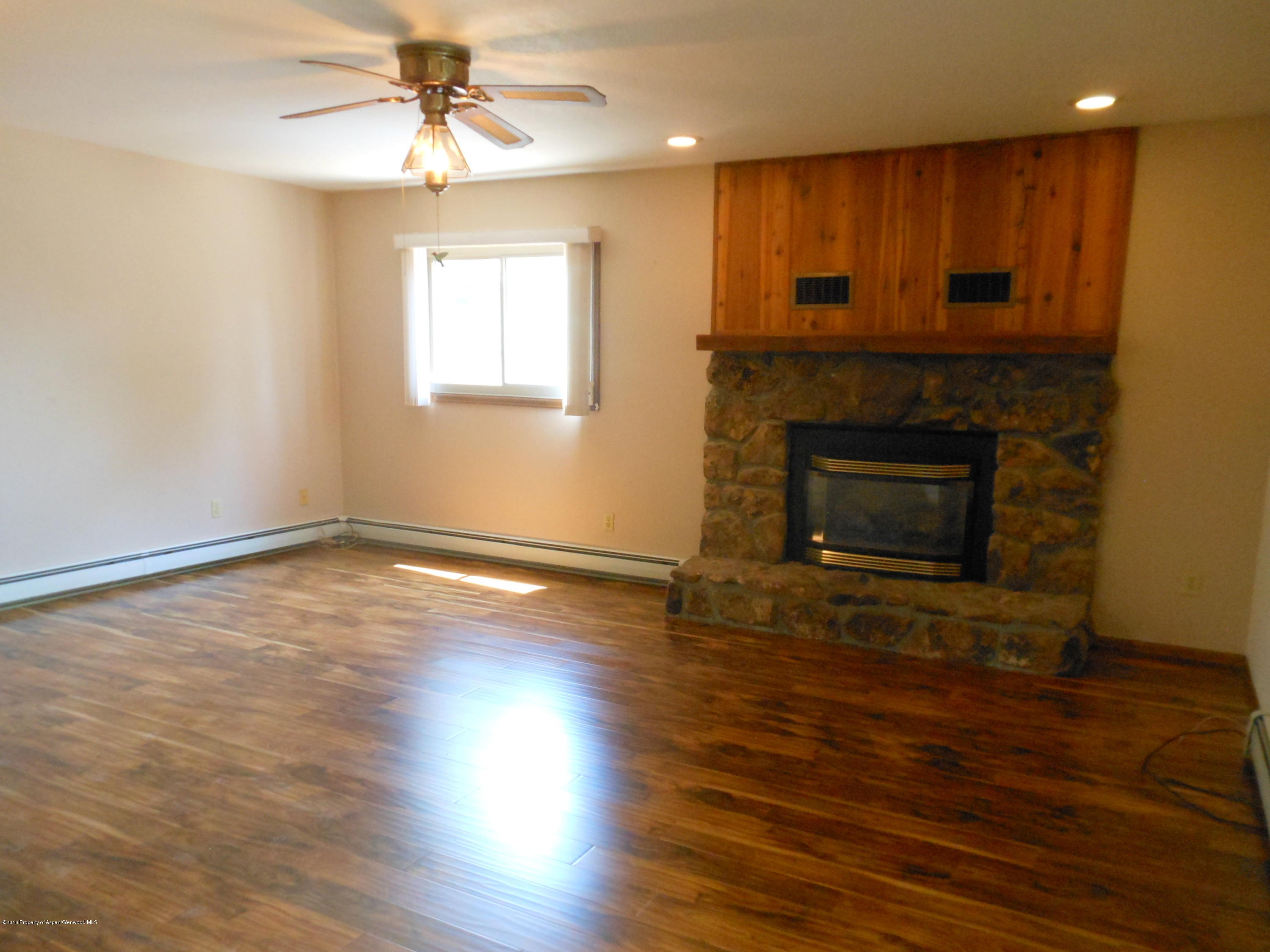 817 Cedar Drive Rifle, CO 81650 - Photo 9 of 24 an empty room with wooden floor a fireplace and windows