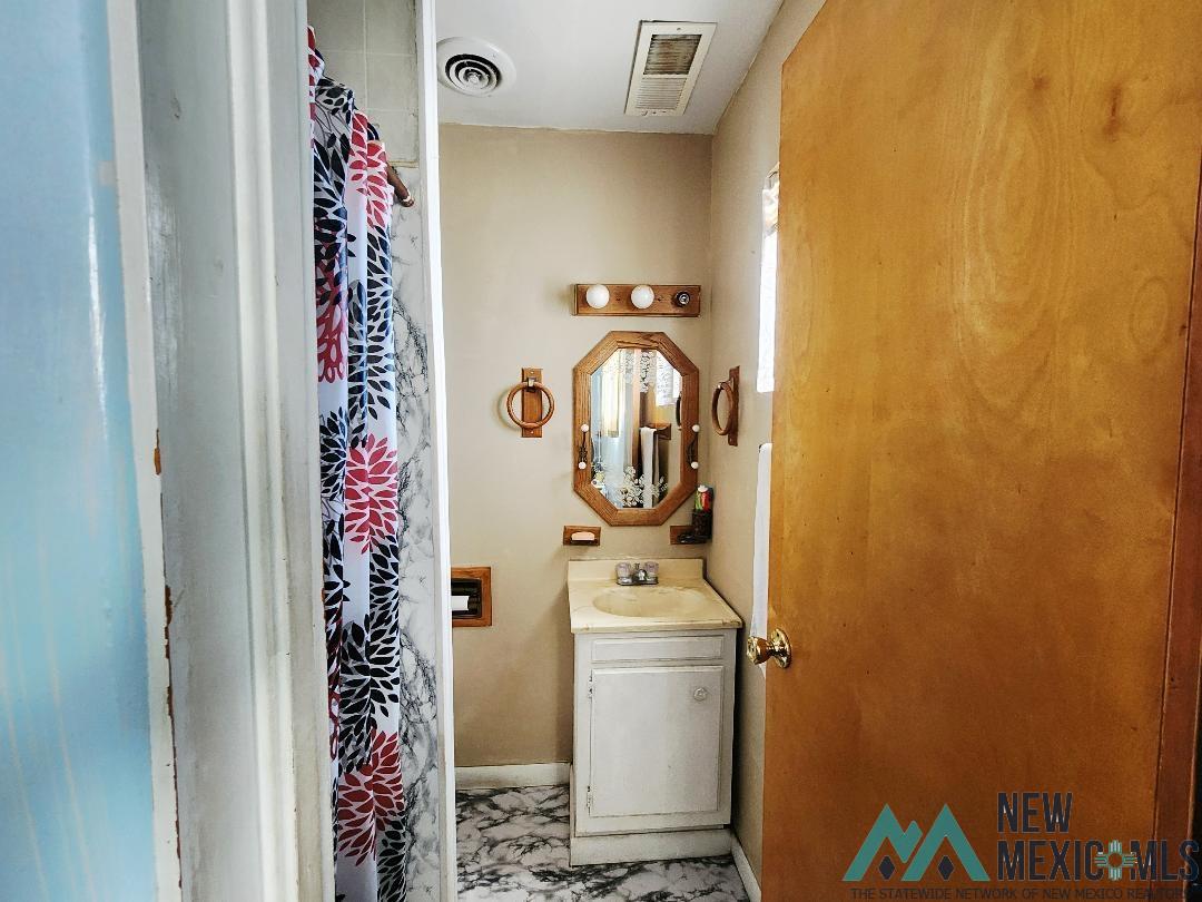 1890 El Portal Road Southeast Deming, NM 88030 - Photo 14 of 21 Full bathroom featuring vanity and a shower with shower curtain