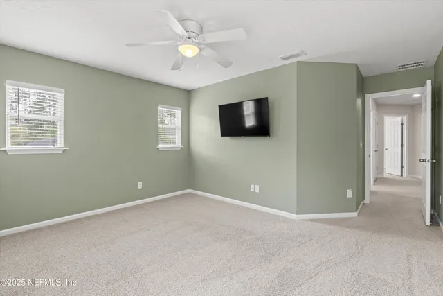 an empty room with windows and fan