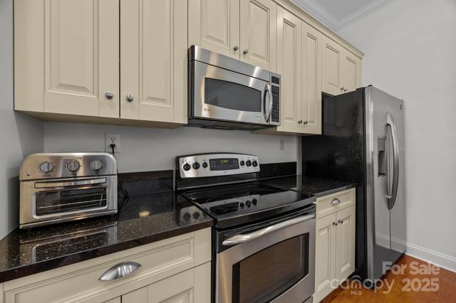 a kitchen with stainless steel appliances granite countertop white cabinets and a stove top oven