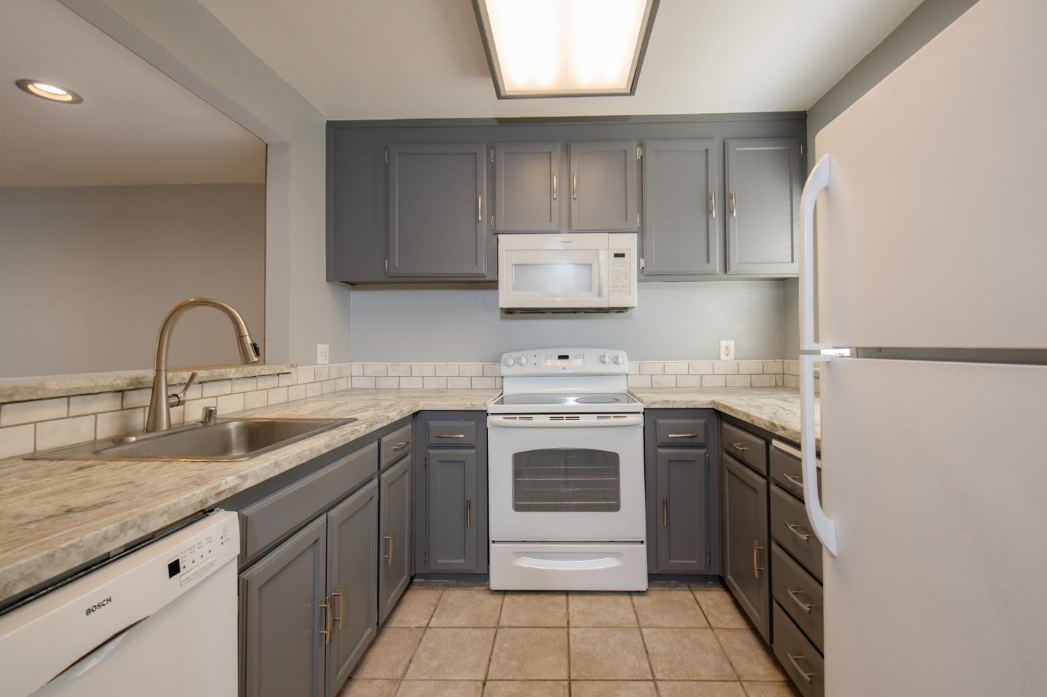 4875 North Backer Avenue, Unit 141 Fresno, CA 93726 - Photo 5 of 23 a kitchen with a sink stove and cabinets