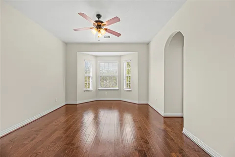 an empty room with wooden floor chandelier and windows