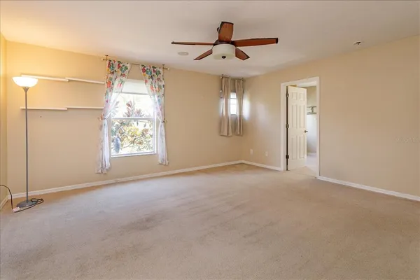 an empty room with windows and ceiling fan