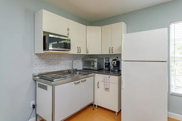 a kitchen with stainless steel appliances granite countertop white cabinets a refrigerator a sink a stove a microwave and cabinetry