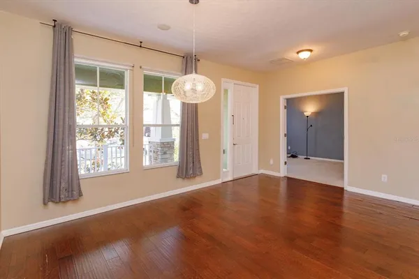 a view of an empty room with a window and wooden floor