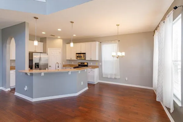 a kitchen with stainless steel appliances kitchen island granite countertop a refrigerator a sink a stove a microwave and white cabinets