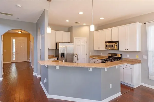 a kitchen with stainless steel appliances granite countertop a refrigerator a stove and a microwave with wooden floor